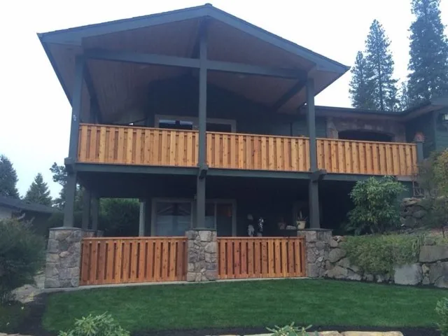 Large covered wood deck with cedar railings and stone columns