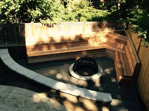 Curved deck with built-in wood benches surrounding a fire pit